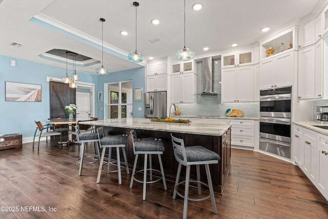 182 N Ridge Dr, Fleming Island, FL 32003 - kitchen featuring wall chimney exhaust hood, appliances with stainless steel finishes, a warming drawer, decorative backsplash, and dark wood-type flooring