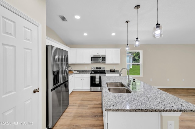 1902 Gillis St, Palatka, FL 32177 - kitchen with appliances with stainless steel finishes, a sink, white cabinets, light wood-style floors, and an island with sink