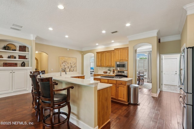 1700 Eagle Watch Dr, Fleming Island, FL 32003 - kitchen with arched walkways, appliances with stainless steel finishes, a center island with sink, light countertops, and dark wood-type flooring