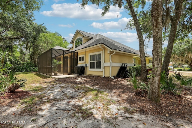 1700 Eagle Watch Dr, Fleming Island, FL 32003 - rear view of house with glass enclosure, stucco siding, and a shingled roof