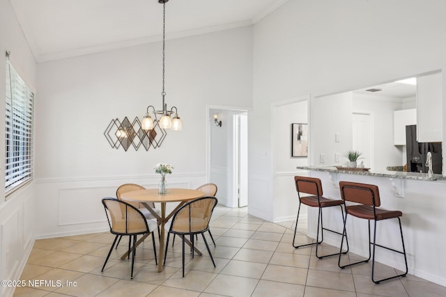 9250 Arbolita Way, Jacksonville, FL 32256 - dining room with a chandelier, ornamental molding, a towering ceiling, light tile patterned floors, and a wainscoted wall