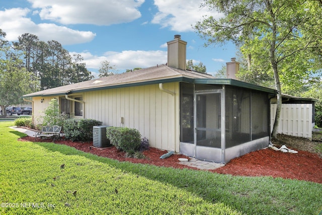 9250 Arbolita Way, Jacksonville, FL 32256 - view of home's exterior featuring a chimney, a sunroom, a lawn, and cooling unit
