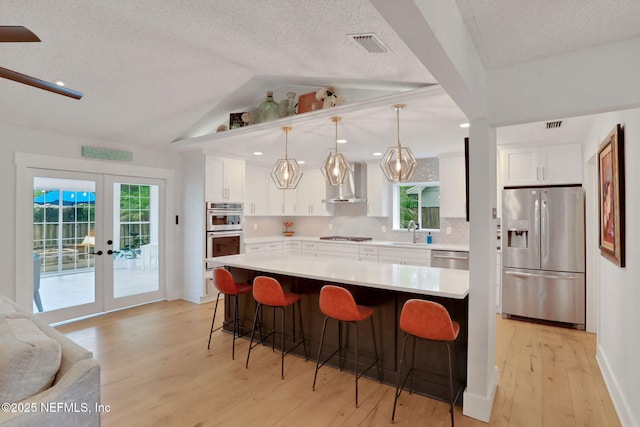 1257 12th St N, Jacksonville Beach, FL 32250 - kitchen with appliances with stainless steel finishes, wall chimney range hood, a sink, light wood finished floors, and backsplash