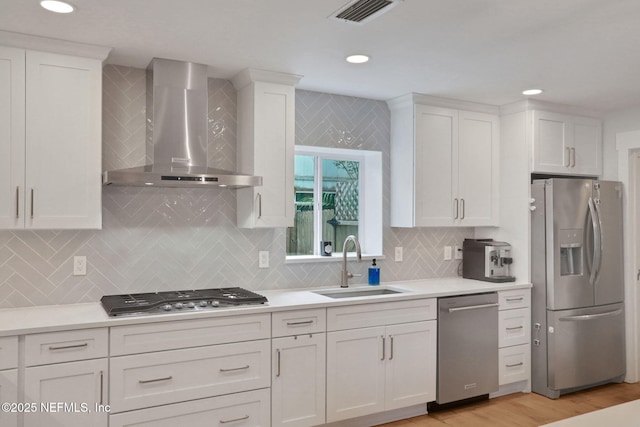 1257 12th St N, Jacksonville Beach, FL 32250 - kitchen featuring stainless steel appliances, wall chimney exhaust hood, a sink, white cabinetry, and light countertops