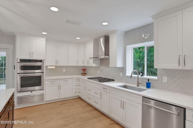 1257 12th St N, Jacksonville Beach, FL 32250 - kitchen with stainless steel appliances, a warming drawer, wall chimney range hood, a sink, and white cabinetry