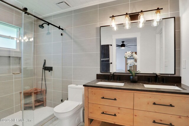 1257 12th St N, Jacksonville Beach, FL 32250 - bathroom featuring tile walls, toilet, a shower stall, double vanity, and a ceiling fan