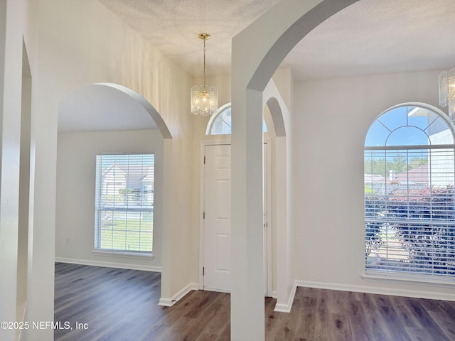 entrance foyer featuring wood finished floors, a chandelier, baseboards, and a textured ceiling