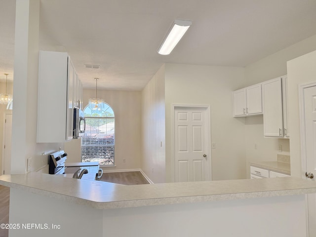 kitchen featuring stove, stainless steel microwave, a chandelier, and light countertops