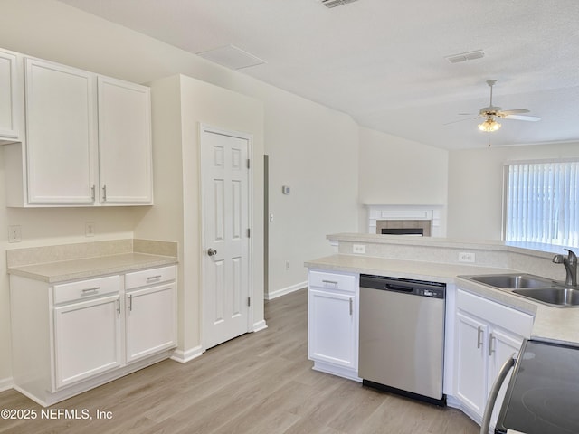 kitchen with stainless steel dishwasher, electric range oven, light wood finished floors, a sink, and white cabinetry