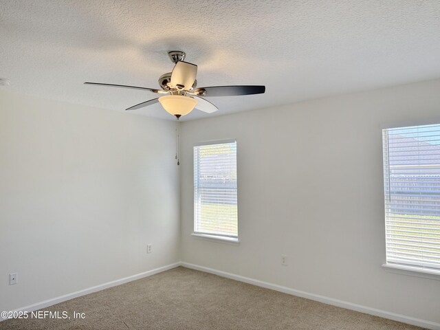 spare room with ceiling fan, light carpet, baseboards, and a textured ceiling
