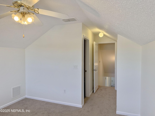 additional living space with light colored carpet, lofted ceiling, ceiling fan, a textured ceiling, and baseboards