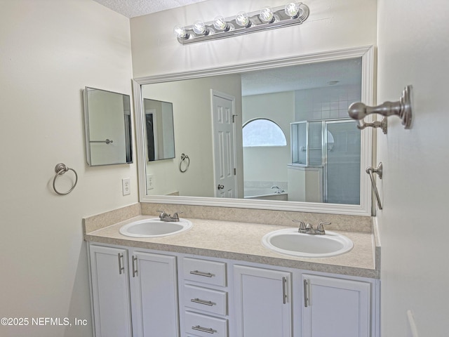 bathroom featuring a shower stall, double vanity, a garden tub, and a textured ceiling