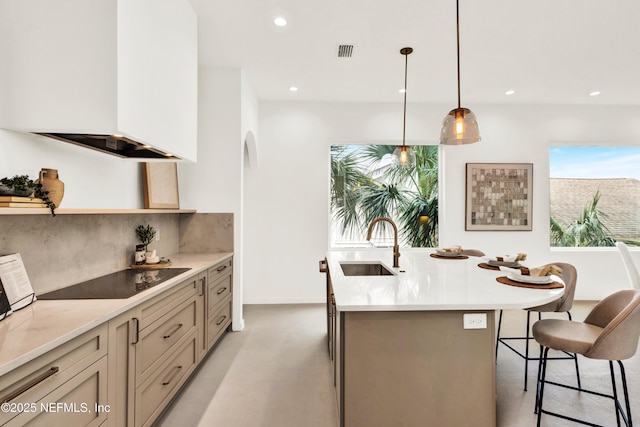 114 12th Ave S Unit 102, Jacksonville Beach, FL 32250 - kitchen featuring black electric cooktop, custom exhaust hood, decorative backsplash, open shelves, and a center island with sink