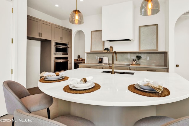 114 12th Ave S Unit 102, Jacksonville Beach, FL 32250 - kitchen with arched walkways, stainless steel double oven, backsplash, hanging light fixtures, and light countertops