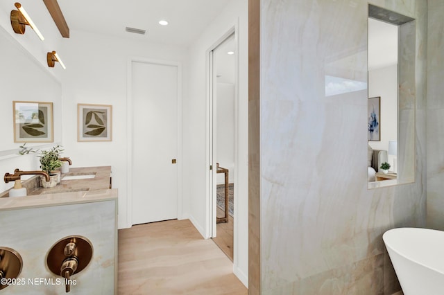114 12th Ave S Unit 102, Jacksonville Beach, FL 32250 - bathroom featuring a soaking tub, vanity, recessed lighting, and wood finished floors