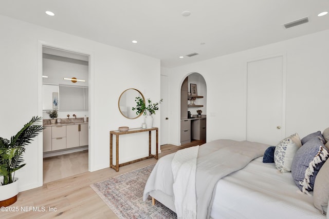 114 12th Ave S Unit 102, Jacksonville Beach, FL 32250 - bedroom with light wood-style floors, arched walkways, recessed lighting, and connected bathroom