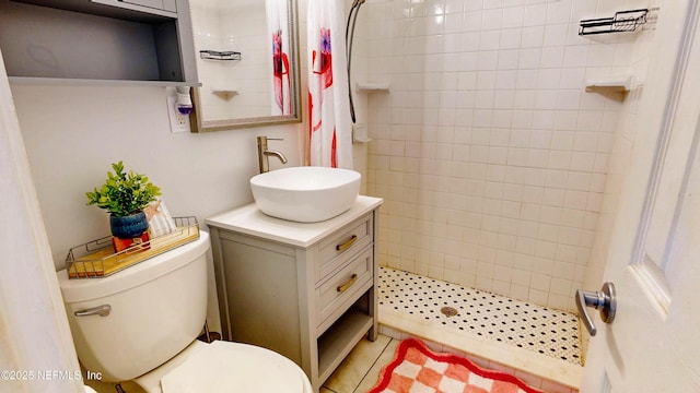 full bath with a tile shower, vanity, and toilet