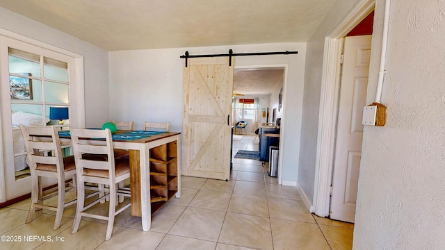 dining space with a barn door, light tile patterned floors, and baseboards