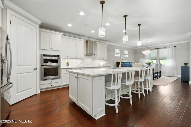 123 Tree Side Ln, Ponte Vedra, FL 32081 - kitchen featuring ornamental molding, wall chimney exhaust hood, a kitchen island with sink, white cabinets, and stainless steel appliances