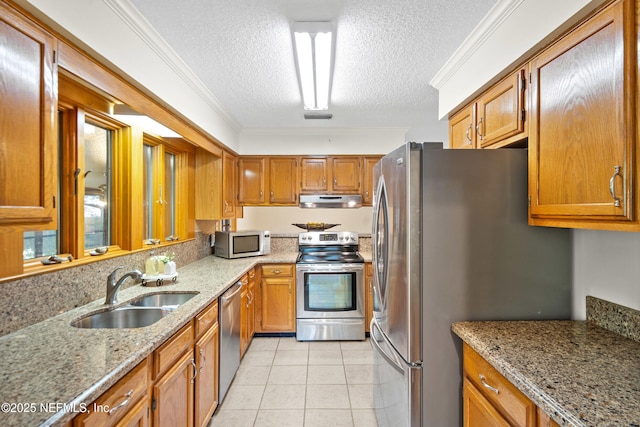 kitchen with stainless steel appliances, exhaust hood, a sink, a textured ceiling, and light stone counters