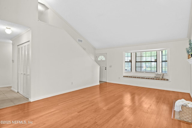 unfurnished living room with crown molding, wood finished floors, and baseboards