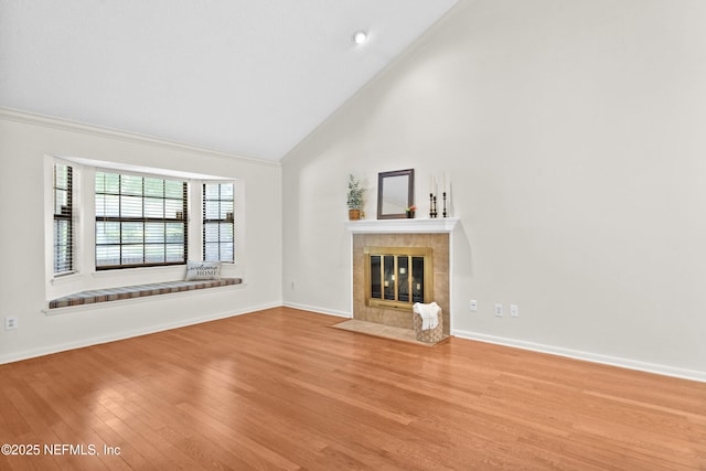 unfurnished living room with wood finished floors, a fireplace, baseboards, high vaulted ceiling, and crown molding