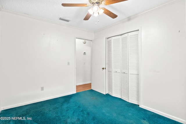 unfurnished bedroom featuring carpet floors, a closet, crown molding, a ceiling fan, and baseboards