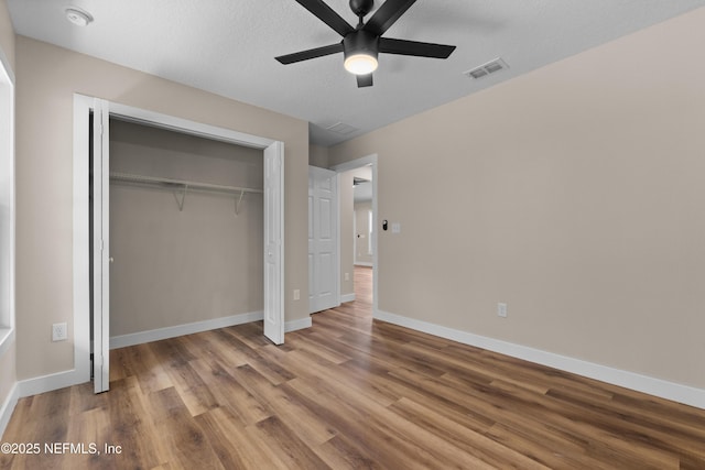 unfurnished bedroom with wood finished floors, baseboards, a closet, and a ceiling fan