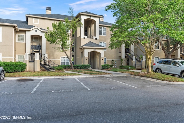1655 The Greens Way Unit 2432, Jacksonville Beach, FL 32250 - view of front of property with stairway, stucco siding, uncovered parking, and a chimney