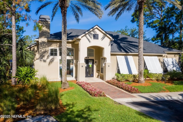 1655 The Greens Way Unit 2432, Jacksonville Beach, FL 32250 - view of front of home with stucco siding, a chimney, a front yard, and roof with shingles