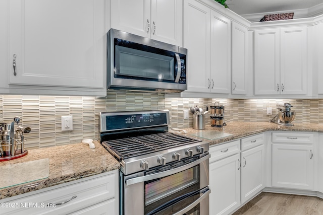 836 Margaritaville Ave, Daytona Beach, FL 32124 - kitchen featuring appliances with stainless steel finishes, white cabinetry, decorative backsplash, and light stone counters