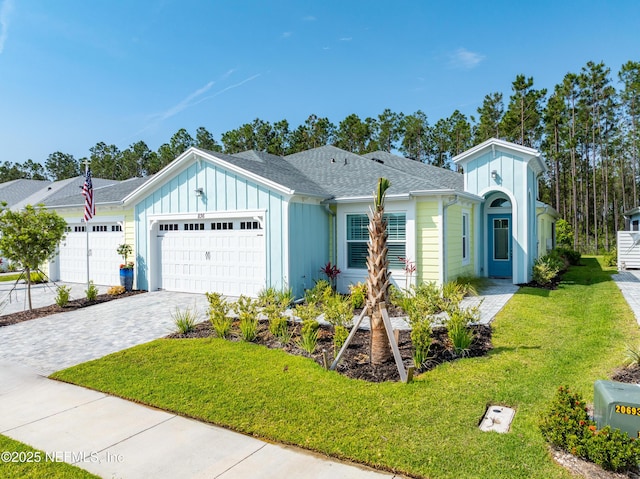 836 Margaritaville Ave, Daytona Beach, FL 32124 - view of front of property featuring a garage, board and batten siding, a front yard, decorative driveway, and roof with shingles