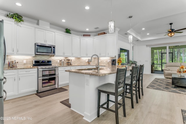 836 Margaritaville Ave, Daytona Beach, FL 32124 - kitchen with appliances with stainless steel finishes, a sink, open floor plan, light wood-style flooring, and crown molding