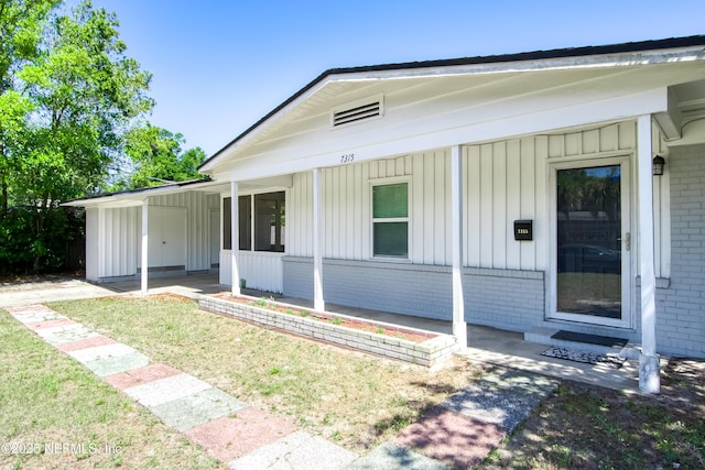 7315 Wonder Ln, Jacksonville, FL 32244 - view of front of house with board and batten siding, brick siding, a front lawn, and an attached carport