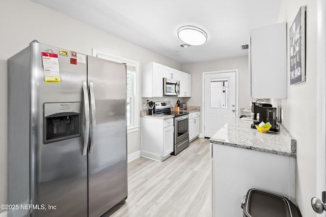 7315 Wonder Ln, Jacksonville, FL 32244 - kitchen featuring appliances with stainless steel finishes, light wood-style floors, white cabinets, and light stone counters
