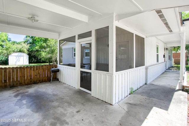 7315 Wonder Ln, Jacksonville, FL 32244 - view of patio featuring a sunroom, a storage unit, fence, and an outdoor structure