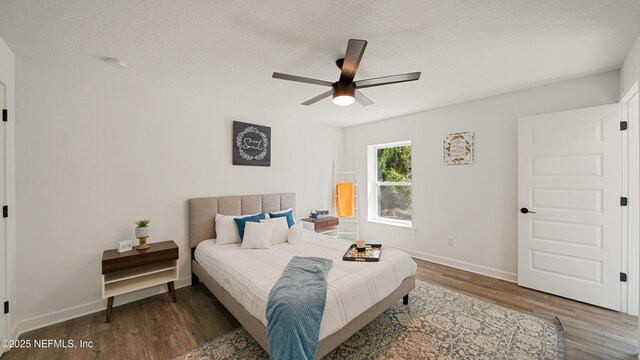 bedroom featuring wood finished floors, baseboards, ceiling fan, and a textured ceiling