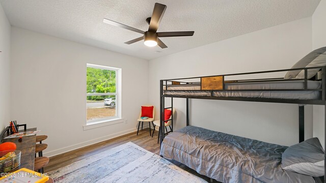 bedroom with wood finished floors, baseboards, a textured ceiling, and ceiling fan