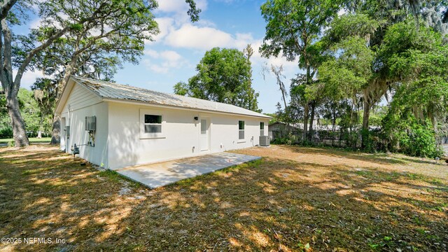 rear view of house with stucco siding, a patio, central air condition unit, and metal roof