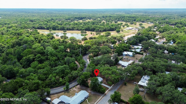 aerial view of property and surrounding area with a forest and a nearby body of water