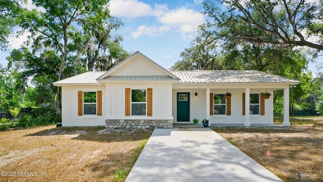 modern farmhouse style home with a porch, metal roof, and board and batten siding