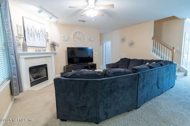 2543 Willow Creek Dr, Fleming Island, FL 32003 - carpeted living room featuring a ceiling fan, stairs, a fireplace with flush hearth, and track lighting