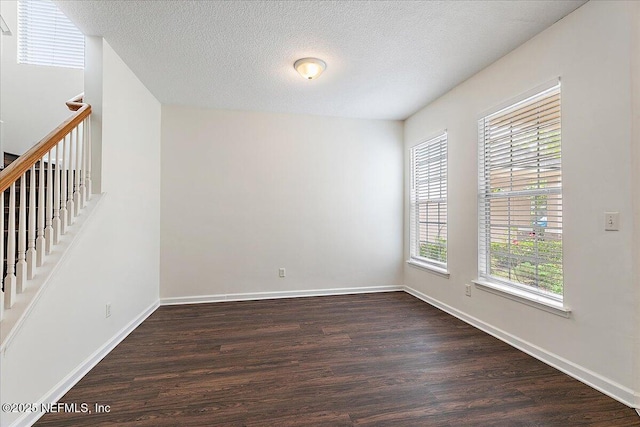 empty room featuring dark wood-style floors, baseboards, and a textured ceiling