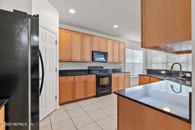 kitchen with black appliances, a sink, light tile patterned floors, dark countertops, and a textured ceiling