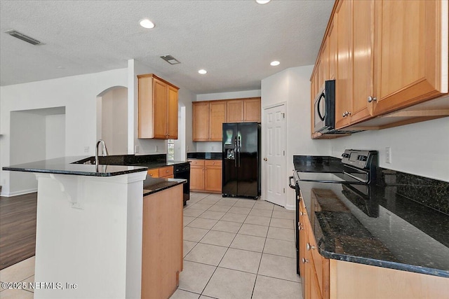 kitchen featuring black appliances, a peninsula, dark stone countertops, recessed lighting, and a textured ceiling