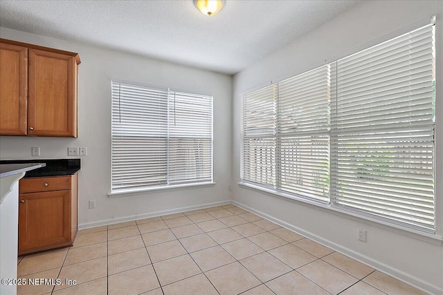 unfurnished dining area featuring healthy amount of natural light, baseboards, and light tile patterned floors