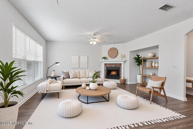 living room with wood finished floors, a ceiling fan, a brick fireplace, baseboards, and arched walkways