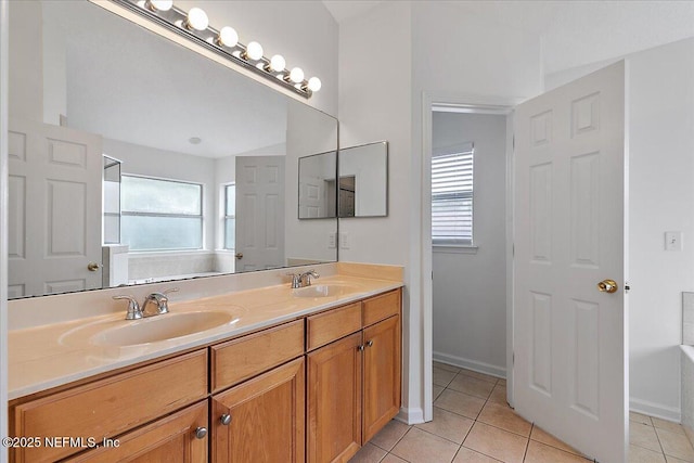 bathroom with tile patterned flooring, double vanity, baseboards, and a tub