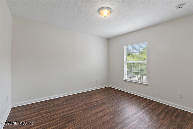 empty room featuring dark wood finished floors, baseboards, a smoke detector, and a textured ceiling