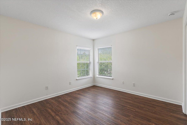 empty room featuring dark wood-type flooring, baseboards, and a textured ceiling